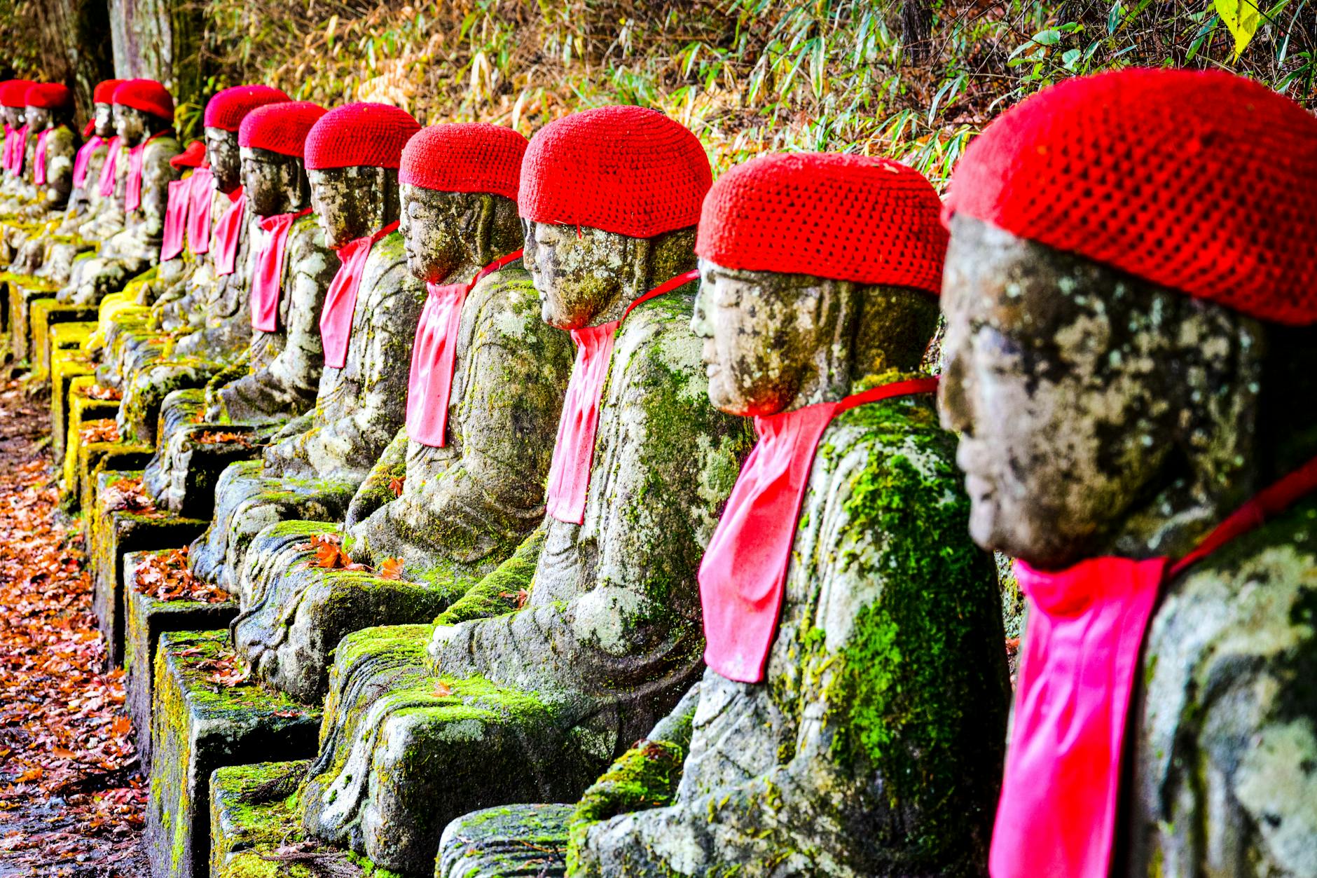 buddha statues decorated with red caps near kanmangafuchi abyss nikko japan
